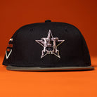 A Daikin Park Olive Houston Astros New Era 5950 Fitted Hat is displayed on an orange surface with an orange background.