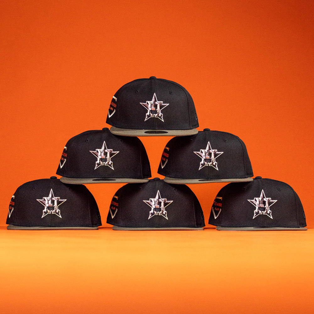 Six Daikin Park Olive Houston Astros New Era 5950 Fitted hats are arranged in a pyramid shape against an orange background, perfect for Astros fans or a day at Daikin Park.