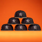 Six Daikin Park Olive Houston Astros New Era 5950 Fitted hats are arranged in a pyramid shape against an orange background, perfect for Astros fans or a day at Daikin Park.