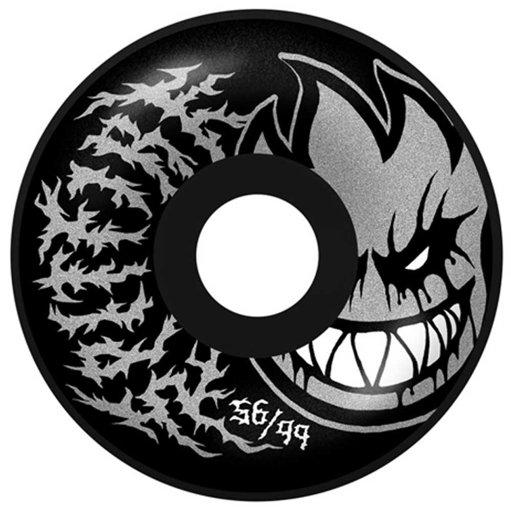 The Deathmask II Radial Full Black 56mm99A Formula Four Spitfire Wheel features a large grinning cartoon face on the right, silver flame-like patterns on the left, and "56/99" printed near the bottom center.