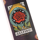 Illustration of a green snake encircling a red rose with leaves and stars, set against a black and white background. Beneath the image, the text reads Delfino Ouroboros Pro 8.25in x 31.60in Santa Cruz Decks, highlighting the premium construction of this 7-ply skateboard deck.