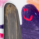 A close-up of a child’s colorful drawing shows a purple figure with a red smiling face beside a brown, wood-textured shape resembling the Diamond Quad Beemer 10.75 Krooked Deck Skateshop Day on a white background.