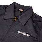 A close-up of the Charcoal Silver Embroidered Old English Black Southside Dickies Unlined Eisenhower Jacket shows "southside" in white Old English on the left chest and a Dickies label inside the collar. This industrial-wash friendly jacket features a zip-up front.