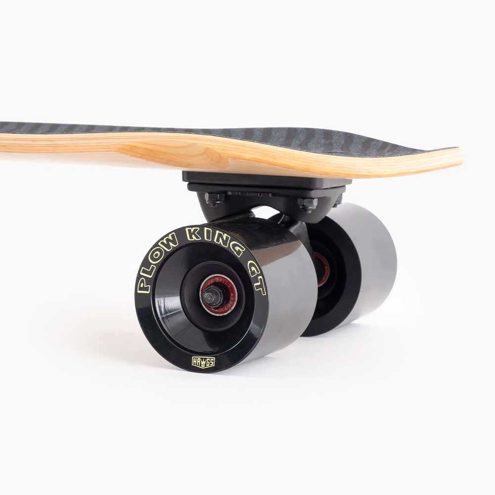 Close-up of the Dinghy Classic Fender Moray Eel Landyachtz Complete Skateboard’s rear wheels and underside, showing black Plow King GT wheels with red bearings, molded wheel flares, and a wood-edged deck on a plain white background.