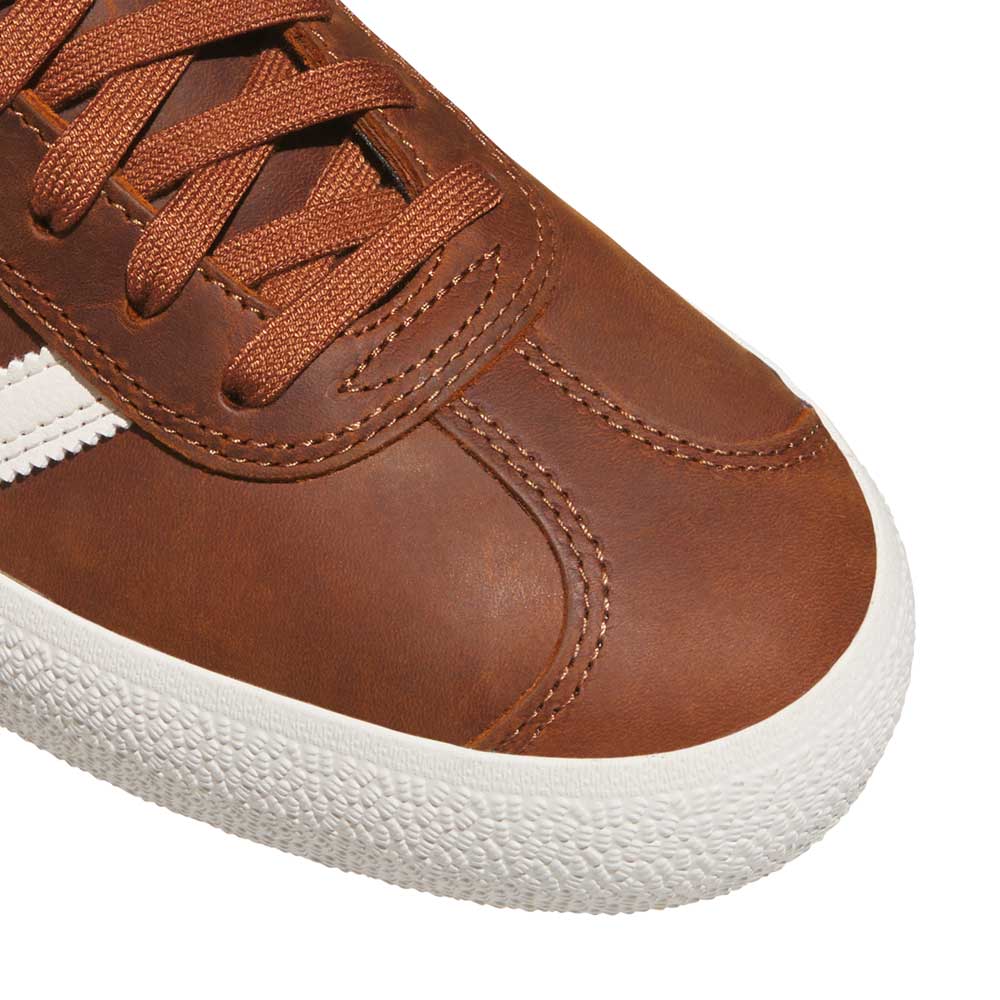 Close-up of the Brown White Gold Gazelle ADV HQ7547 Adidas Skateboarding suede shoe featuring brown laces, white stitching, a white rubber sole, and a white side stripe for a classic skate-inspired look.
