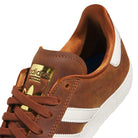 A close-up of the Brown White Gold Gazelle ADV HQ7547 Adidas Skateboarding Suede Shoe, featuring white stripes, brown laces, a gold tongue logo, a textured white sole, and smooth suede for signature skate-inspired style.
