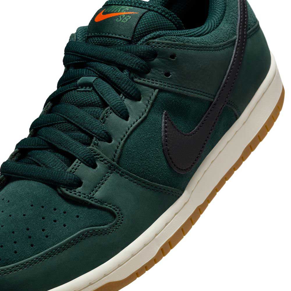 A close-up of the Nike SB Dunk Low Pro FJ1674-300 "Deep Fir Black Fir Sail" shows its dark green suede, black swoosh, orange tongue logo, white midsole, and gum outsole—a true classic for any sneaker collection.
