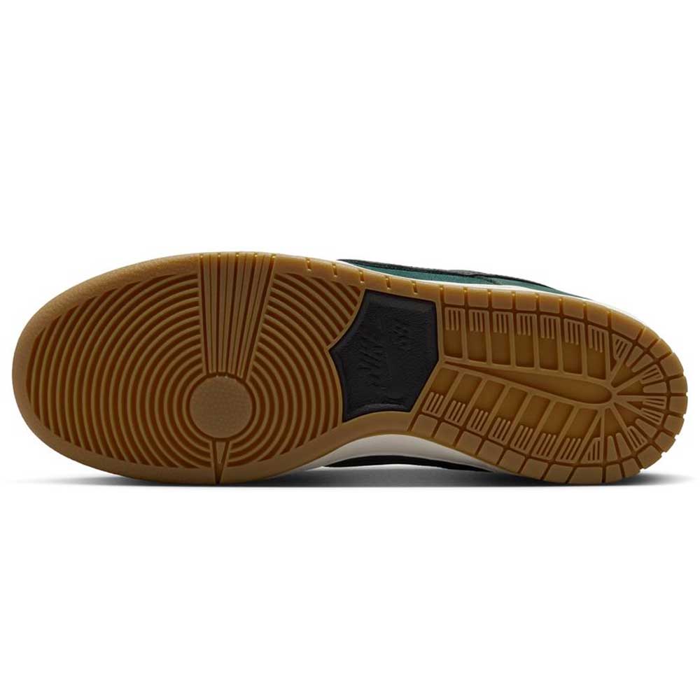 A close-up of the Nike SB Dunk Low Pro FJ1674-300 showcases its tan gum sole with unique circular and geometric tread, plus a black center section—ideal for fans of classic style. This "Deep Fir Black Fir Sail" suede sneaker blends function and heritage.