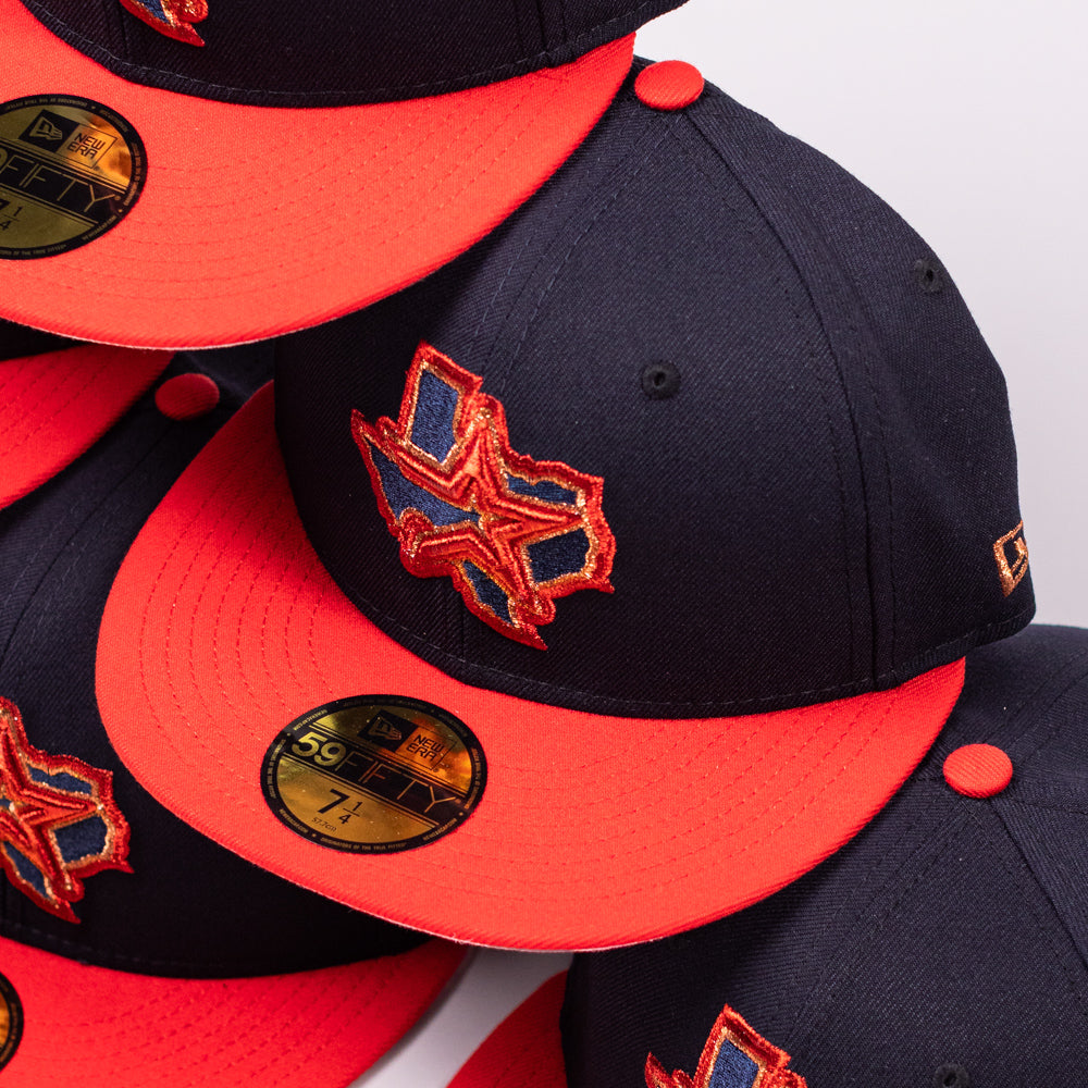 A close-up of several El Karma ASG Navy Red Houston Astros New Era Hat 5950 Fitted caps featuring a striking star and map logo on the front, gold 59FIFTY size stickers on the visors, and signature Houston Astros style—all crafted with classic New Era Hat quality.