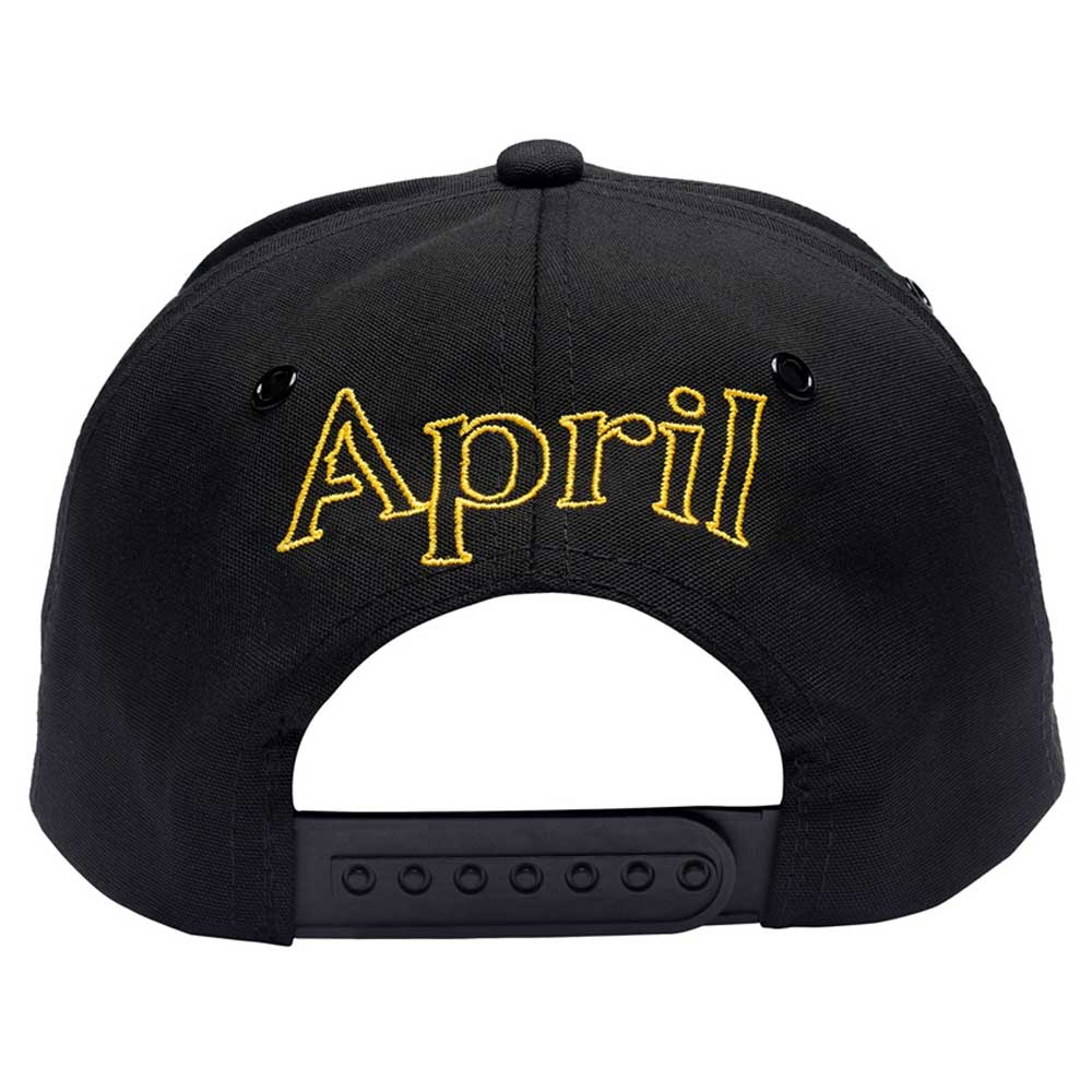 A black adjustable snapback hat from April Skateboards with "April" logo stylishly embroidered in gold above the strap.