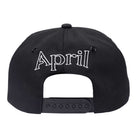 Black Embroidered Logo Hat by April Skateboards, featuring "April" in silver embroidery above an adjustable plastic strap.