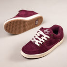 A pair of Accel Burgundy White Suede Es Shoes Skateboarding features white laces and soles. One shoe is upright, showing the top and side, while the other lies on its side to display the tread pattern for skate style.