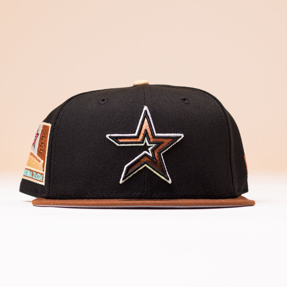 A black Espresso Martini Houston Astros New Era 5950 Fitted Hat featuring a metallic gold outlined star logo on the front and a brown brim, displayed against a neutral background. This cap by Alyyjadee adds a touch of standout style to any look.