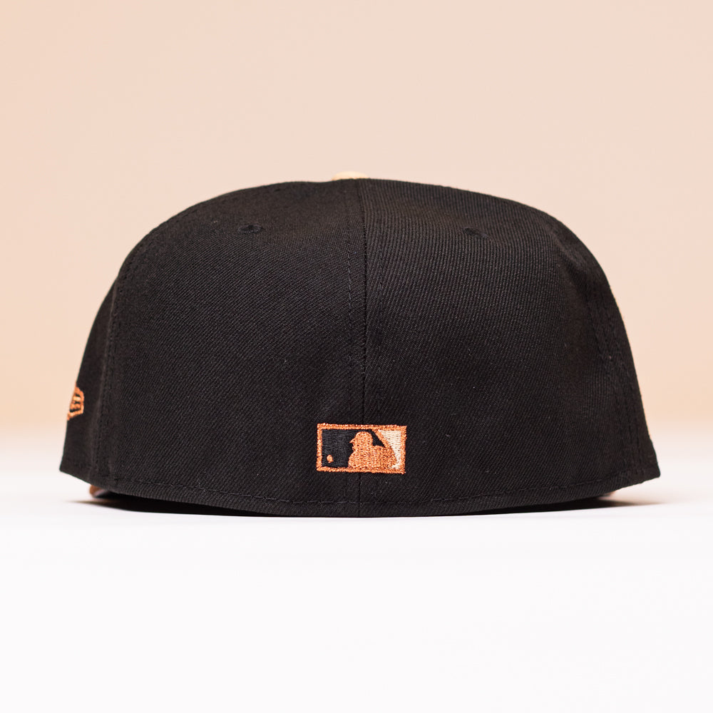 Back view of the Espresso Martini Houston Astros New Era Hat 5950 Fitted, featuring a small orange MLB logo embroidered near the bottom edge. This cap combines sleek style with authentic team detail.