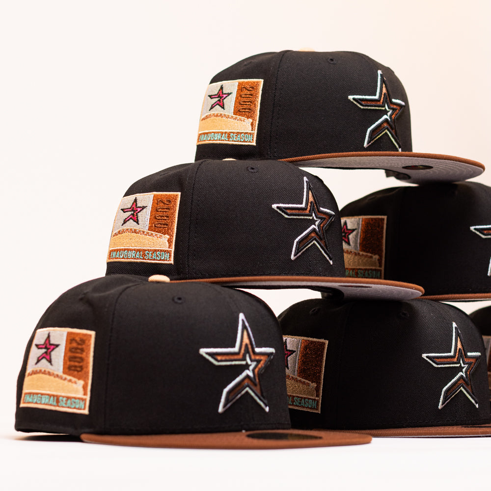 Six Espresso Martini Houston Astros New Era 5950 Fitted hats are stacked, each featuring a black crown, brown brim, the signature Houston Astros star logo on the front, and a 2000 Inaugural Season patch on the side—highlighting the unique Alyyjadee design.