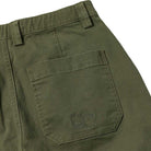 The Eternal Pant Olive Spitfire Wheels features a close-up of the back pocket with two subtle embroidered logos: a Spitfire Wheels flame with a face, and another circular logo with text and a face.