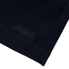 Close-up of the Eyes Twill Short in light navy from Krooked Skateboards, showing its subtle diagonal twill texture and a stitched rectangular patch with "GROOVE" embroidered in tonal thread near the hem.