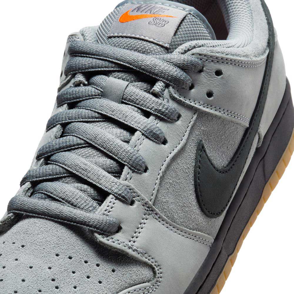 Close-up of the FJ1674002 Cool Grey Black Nike SB Dunk Low Pro Suede Shoes, featuring grey suede and mesh, a black Swoosh, gum sole, and orange Nike SB branding on the tongue—perfect for classic sneaker fans.
