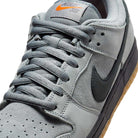 Close-up of the FJ1674002 Cool Grey Black Nike SB Dunk Low Pro Suede Shoes, featuring grey suede and mesh, a black Swoosh, gum sole, and orange Nike SB branding on the tongue—perfect for classic sneaker fans.
