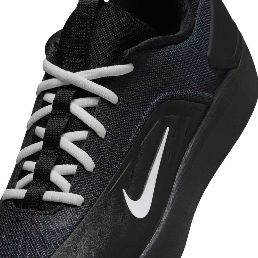 Close-up of the FQ1273002 Black White Zoom Nyjah 4 Nike SB skateboarding shoe with white laces, a bold white Swoosh, reinforced mesh upper for durability, and a smooth black sole.
