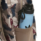 A blue water bottle with a black cap sits in the side pocket of the FSBS Backpack KS6815 Khaki Camo from adidas Skateboarding, showcasing its stylish camouflage pattern and practical design.