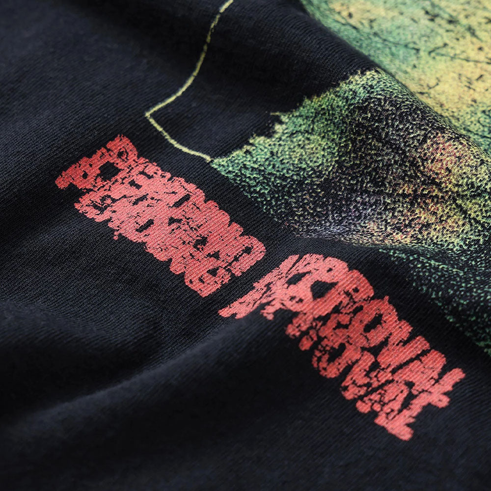 A close-up of black fabric from the Mind Glass Former Tee Black, featuring red distorted text and green textured graphics screen printed on it, showcasing its unique design.