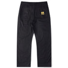A pair of Reynolds Work Pant Black Former is displayed from the back, showcasing two rear pockets. One pocket is adorned with a small yellow and black rectangular patch label, adding a distinctive touch to these baggy work pants inspired by the Dane Reynolds style.