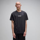 A man with short hair stands against a plain background, wearing the Legacy Overdye Former Tee in washed black. This vintage-style T-shirt is crafted from premium 200GSM cotton and features the word FORMER screen printed in white across the chest.