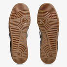 Two brown rubber soles from the ASICS Gel Vikka Pro Black Brown Suede Skateboarding Shoes (model 1201A486) feature a circular tread pattern and the ASICS logo at the center, optimized for enhanced board control, displayed side by side on a white background.