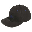 The Gonz Cap Black Blue KS6799 Adidas Hat features blue stitched accents and a blue embroidered logo on the front, shown from a side angle. It’s adjustable for a comfortable fit.