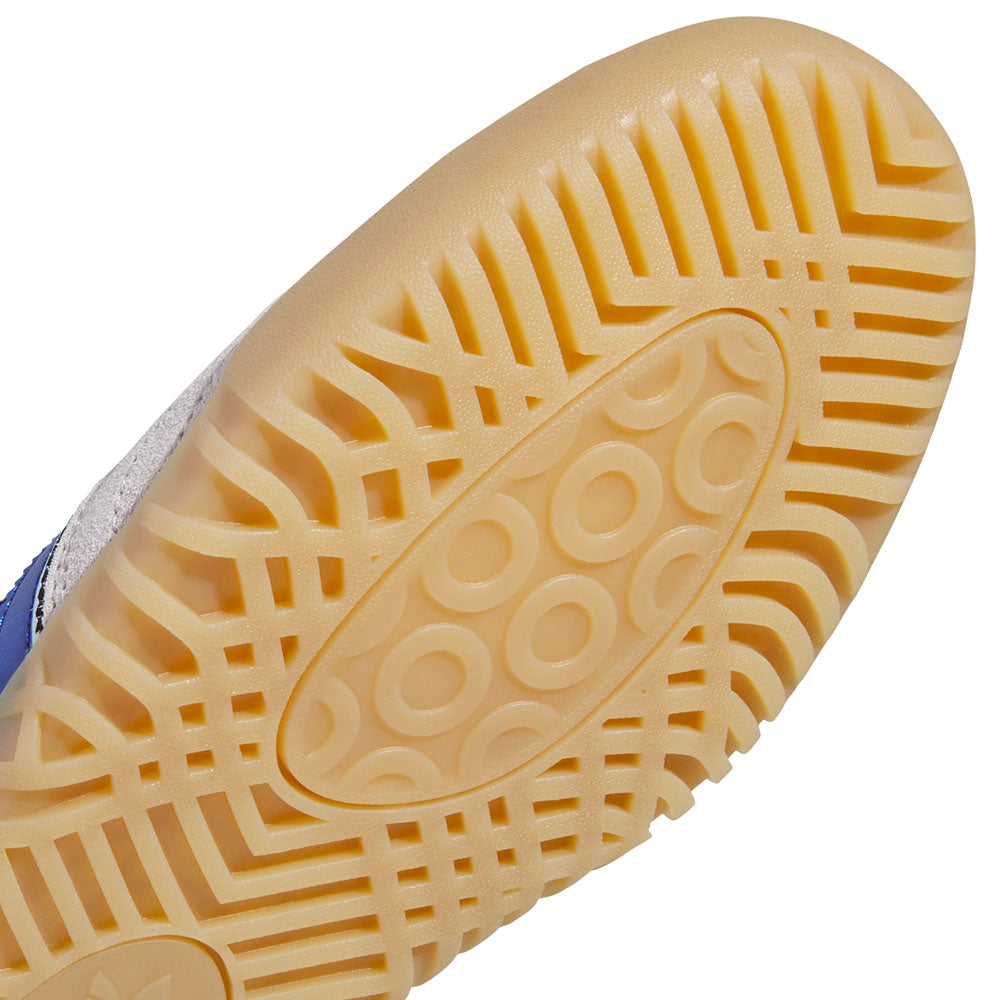 Close-up of a yellow rubber sole with a textured pattern of circles and angled grooves, attached to the Gray Royal Blue KZ8895 Busenitz Indoor Adidas Skateboarding Suede Shoes Footwear—sneakers inspired by the iconic Busenitz Indoor Super model.