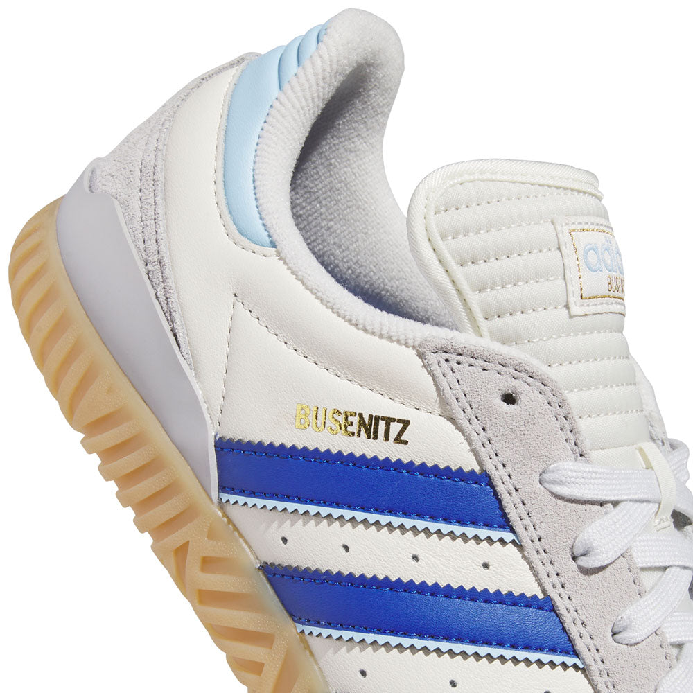 Close-up of the Gray Royal Blue KZ8895 Busenitz Indoor Adidas Skateboarding Suede Shoes, featuring bold royal blue stripes, gold BUSENITZ branding, a gum sole, and a light blue heel accent. The upper is crafted from white leather with a textured, padded tongue and suede details near the laces for added durability and style—perfect for skateboarding.