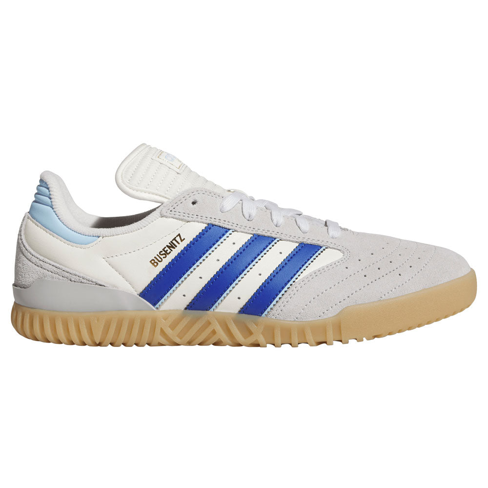 A gray Adidas Busenitz Indoor skateboarding shoe, model KZ8895, with royal blue stripes, a gum sole, and “BUSENITZ” written in gold above the stripes. The shoe features suede construction with perforations on the toe area and a light blue detail on the heel.