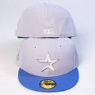 Two light gray Peoples Champ Gray Blue Houston Cougars New Era Hat 5950 Fitted caps are stacked, each featuring blue flat brims and visible stitching. The front cap displays a metallic star logo, while the back cap shows a small white emblem on the rear—making these hats perfect for Houston Cougars fans seeking standout style.