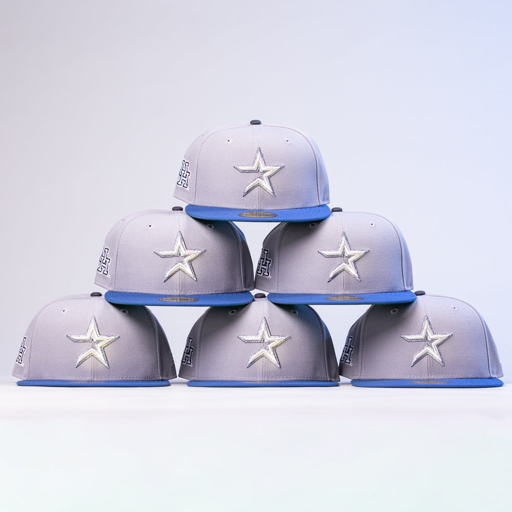 Six Peoples Champ Gray Blue Houston Cougars New Era Hat 5950 Fitted caps, each featuring a white star logo and blue brim, are stacked in a pyramid shape against a plain background, showcasing their classic New Era style.