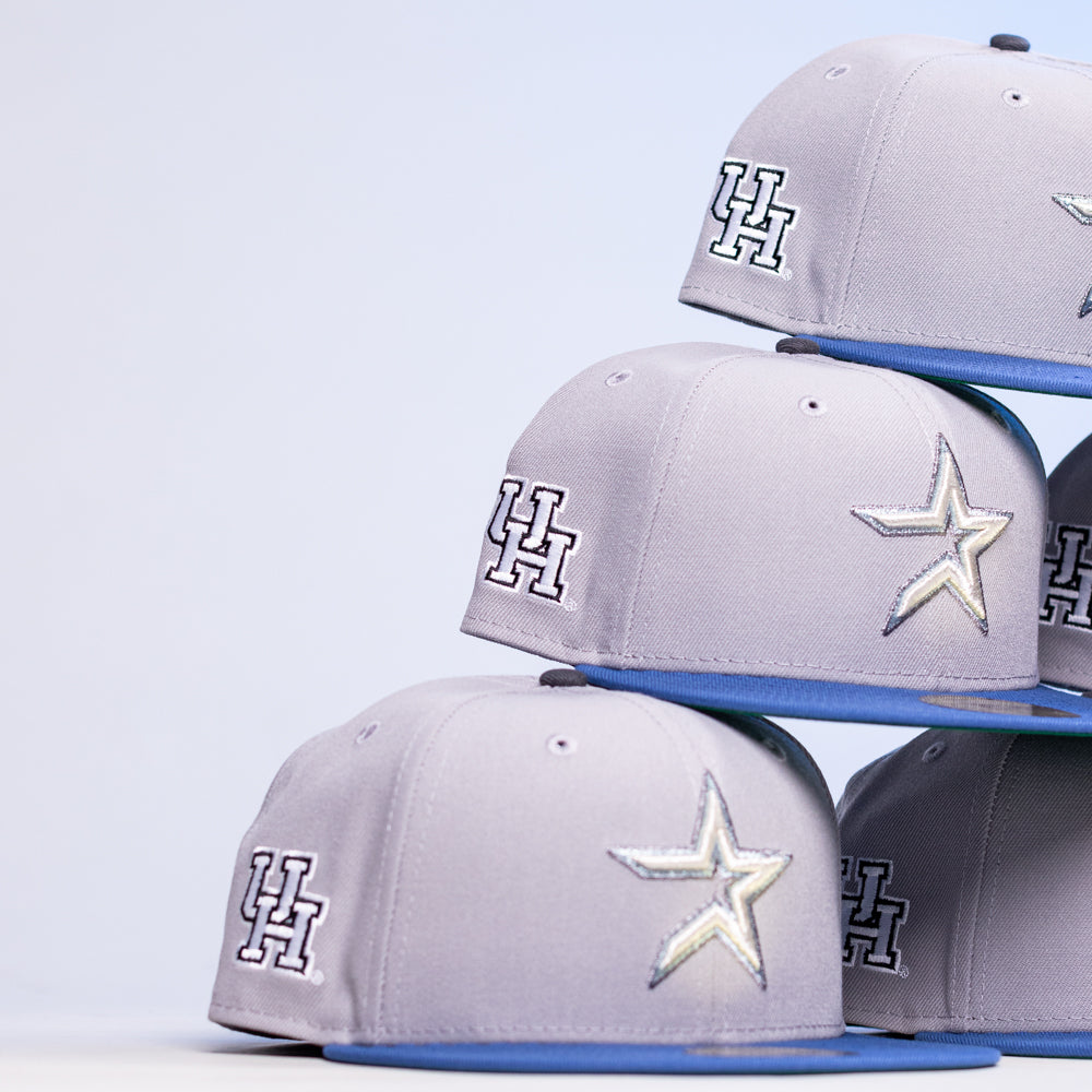 Four Peoples Champ Gray Blue Houston Cougars New Era Hat 5950 Fitted baseball caps are stacked diagonally against a white background.