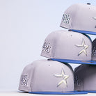 Four Peoples Champ Gray Blue Houston Cougars New Era Hat 5950 Fitted baseball caps are stacked diagonally against a white background.