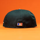 The Greenhand RTC Oil Houston Astros New Era Hat 5950 Fitted is shown from the back, highlighting the embroidered MLB logo against a solid orange background.