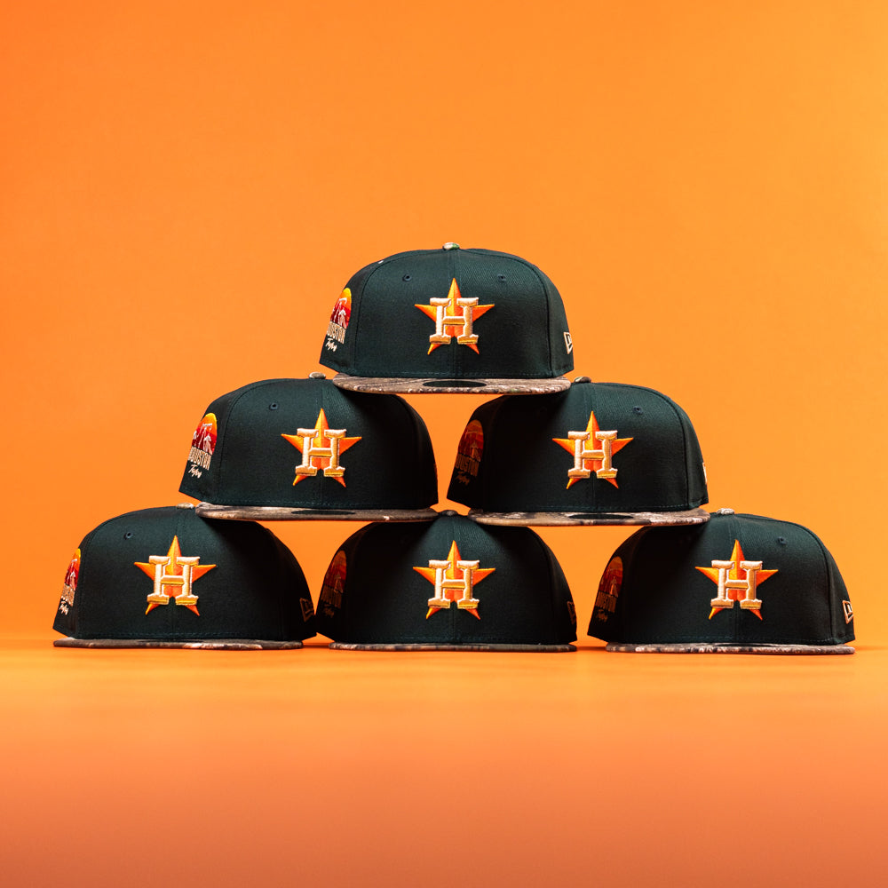 Six Greenhand RTC Oil Houston Astros New Era Hat 5950 Fitted caps are stacked in a pyramid against an orange background, each featuring the team's orange star logo with an H on the front.