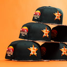 Several Greenhand RTC Oil Houston Astros New Era Hat 5950 Fitted caps, featuring unique patch designs, are stacked in a pyramid against an orange background.