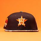 The Old Head RTC Wood Oil Houston Astros New Era 5950 Fitted Hat features a gold star and orange H logo, a patterned brim, and a colorful side patch, shown against an orange background.