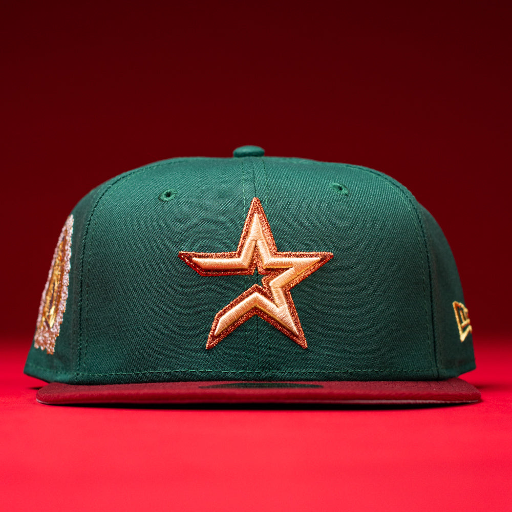 A La Virgencita Green Red Gold New Era Houston Astros Hat 5950 Fitted featuring a green crown with a gold star emblem on the front, maroon brim, gold logo details on the side, and set against a red background. This hat draws inspiration from Mexican culture and Virgen motifs, blending classic style with unique accent details.