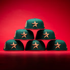 Five La Virgencita Green Red Gold New Era Houston Astros Hat 5950 Fitted caps, featuring vibrant green fabric with gold-outlined stars inspired by Mexican culture, are stacked in a pyramid shape on a red background.