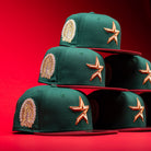 Five La Virgencita Green Red Gold New Era Houston Astros 5950 Fitted hats, inspired by Mexican culture and classic La Virgencita designs, are stacked in a pyramid on a bright red background.