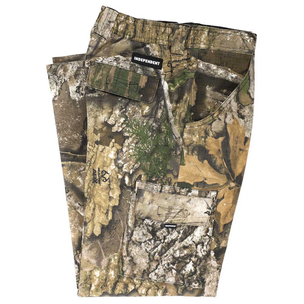 A pair of folded Groundwork 2 Cargo Pants Realtree APX Bottom Mens by Independent, crafted from durable camouflage ripstop fabric with multiple cargo pockets and a visible INDEPENDENT label above one back pocket, displayed on a white background. This rugged apparel piece showcases the authentic REALTREE APX colorway for versatile outdoor style.