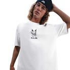 A person with long curly hair in a black Nike beanie and the HV2195100 Max 90 Skate T-Shirt SB Tee White, featuring Nike SB skateboarding screenprint, stands against a white background with one hand behind their head.