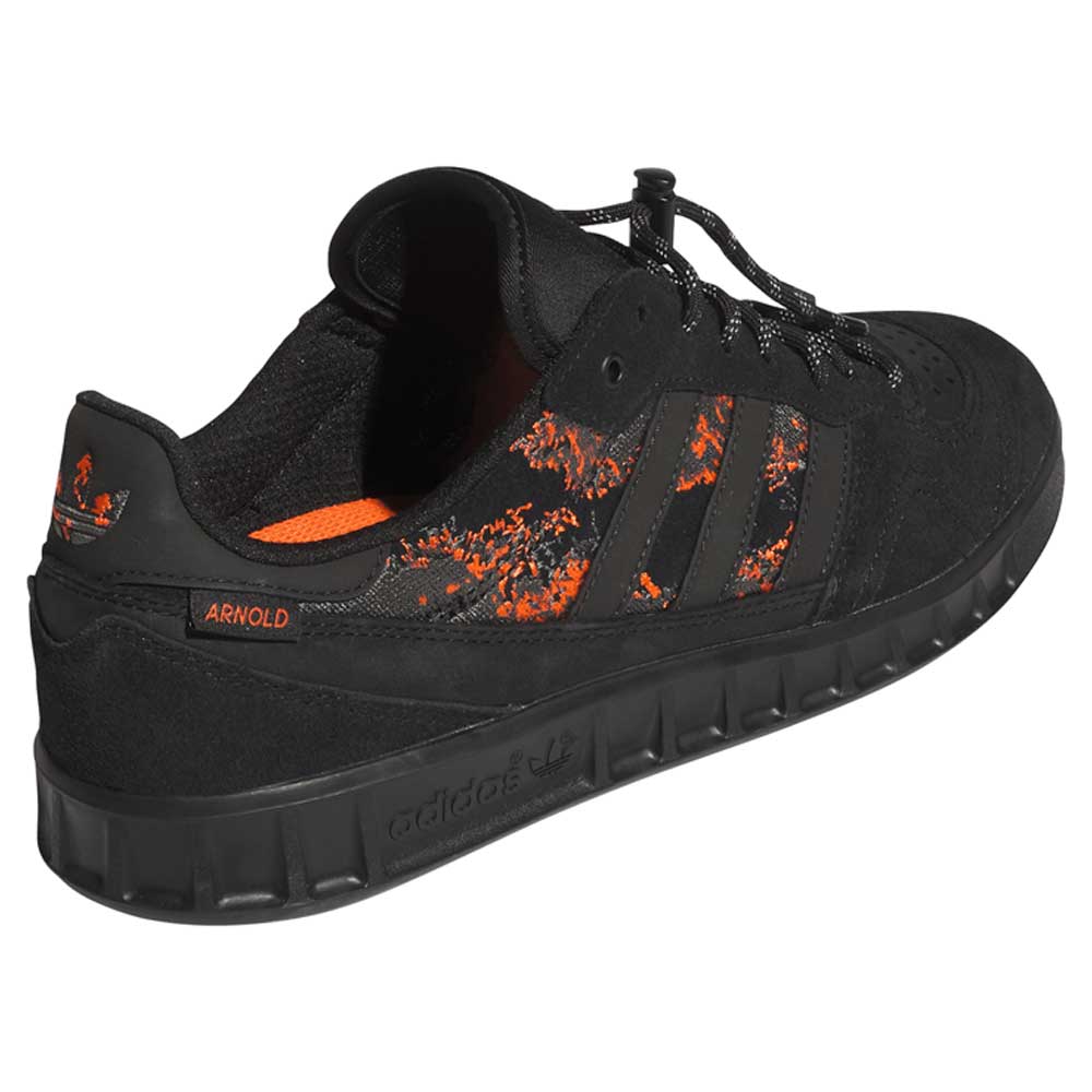 The Handball Top x Mike Arnold Shoes are black suede Adidas Skateboarding sneakers, featuring orange splatter details, black laces, "ARNOLD" on the side, and Adidas logos on the sole and heel for a stylish, bold low-cut look.