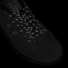 Close-up of the Handball Top x Mike Arnold Shoes: black suede Adidas skateboarding shoes with patterned laces, subtle red and orange side accents, and an Adidas logo by the tongue.