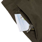 A close-up of a Hecho Por Skate Pant Anti Hero Skateboards Dark Olive pocket with a key and an illustrated postcard—ideal for skateboarders celebrating Skateshop Day.