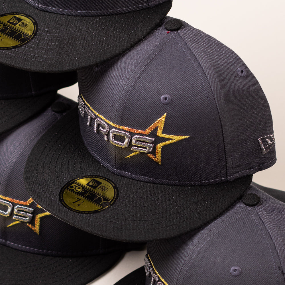 A stack of Black Delta City Connect Houston Astros New Era Hat 5950 Fitted baseball caps, each featuring a metallic gold and silver star logo.